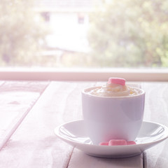 Hot Chocolate with Cream and Marshmallow on White Table in Front of Window with Sunflare and Copy Space