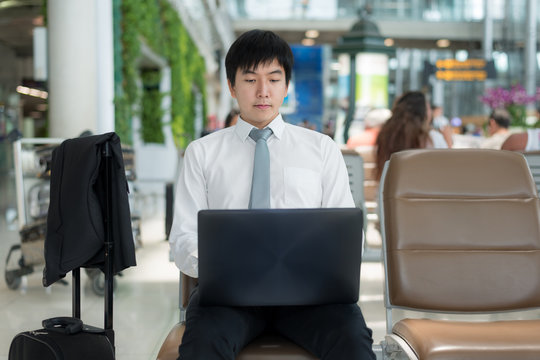 Asian young business traveler using laptop computer in airport 