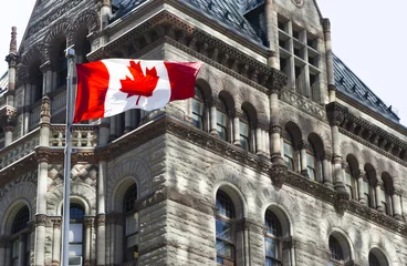 Gordijnen Beautiful Canada flag is waving front of a historical building © COSPV