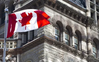 Foto op Aluminium Mooie Canadese vlag zwaait voor een historisch gebouw © COSPV