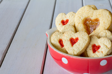 Bowl of Heart Cookies with Different Fillings on a White Wooden Table with Copy Space Horizontal