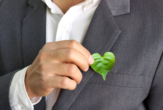 Businessman holding a green heart leaf / Business with corporate social responsibility and environmental concern