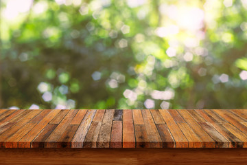 Empty wooden table with bokeh abstract green background.