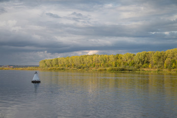 autumn water landscape. buoy on the water, evening river and forest on the banks
