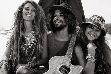 Attractive boho man and women sitting on pillows at tepee