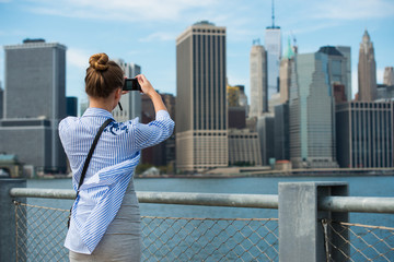 Tourist woman taking travel picture with camera of Manhattan Skyline and New York City skyline...