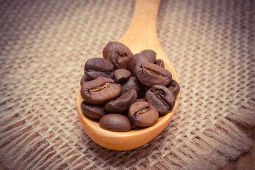Vintage photo, Heap of coffee beans with wooden spoon on jute canvas