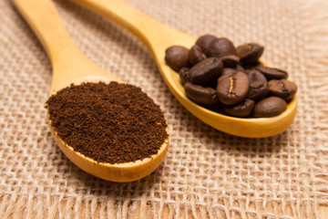 Ground coffee and grains with wooden spoon on jute canvas