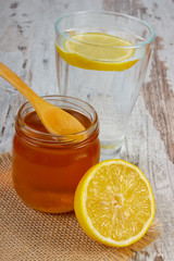 Fresh lemon with honey and glass of water with slice of lemon
