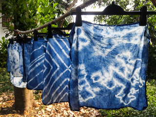 Beautiful natural indigo tie dye fabric with garden view in background. - obrazy, fototapety, plakaty