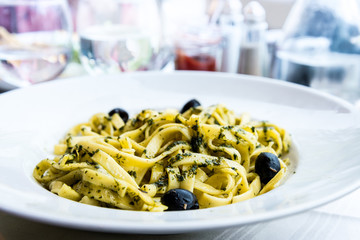 Pasta with pesto sauce and nuts on a the table