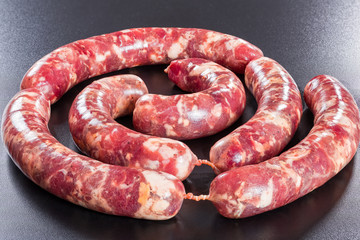 fresh raw meat sausages on black background