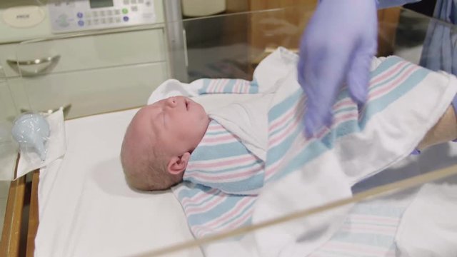 Newborn Baby in Hospital Swaddled by Nurse