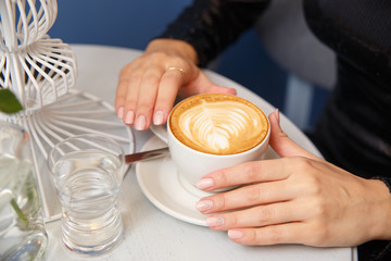 Close-up female hands holding cup with coffee
