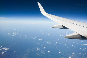 Airplane wing during flight over the blue sky