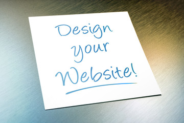 Design Your Website Paper Lying On Brushed Aluminum Of Refrigerator
