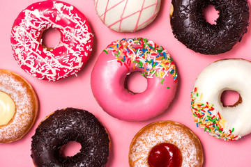 Donuts with icing on pastel pink background. Sweet donuts.