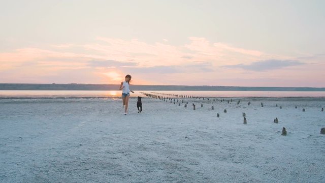 Young female playing and training labrador retriever dog on the beach at sunset, slow motion