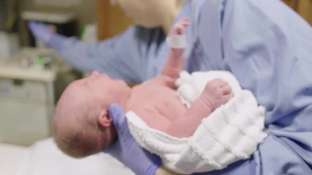 Nurse Cleans Head of Newborn Baby After Birth in Hospital