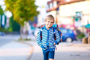 little kid boy with school satchel on way to school 