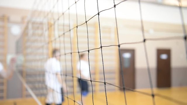 Playing volleyball in the gym. Grid closeup
