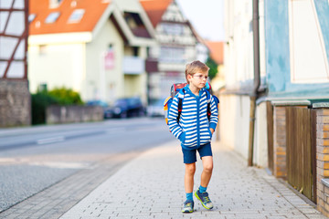 little kid boy with school satchel on way to school 