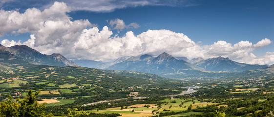 Champsaur Valley and Drac River with clouds. Hautes-Alpes in summer. The panoramic view includes the mountain peaks: Palastre, Soleil Boeuf, Grande Autane, Petite Autane and Aiguille. France