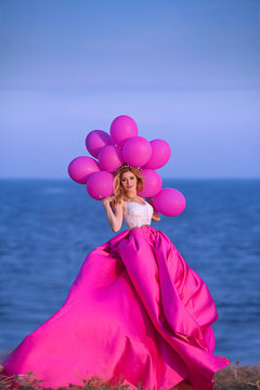 Young woman holding pink balloons