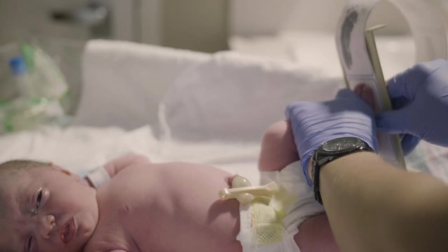 Nurse in Hospital Holds Ink Footprint Strip by Newborn Baby After Birth