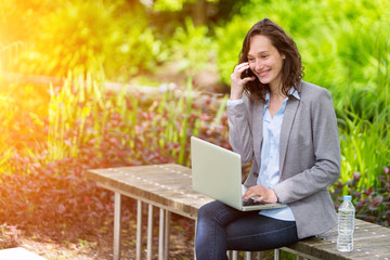 Young attractive business woman working at the park during a pau