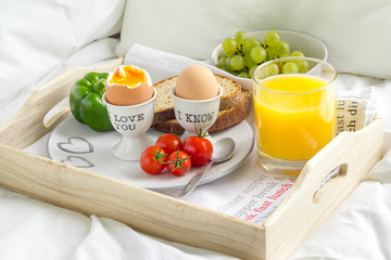 Breakfast served in bed on a wooden tray.