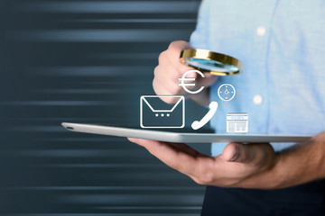 Businessman holding magnifying glass and tablet. Digital media icons on screen. Technology concept.