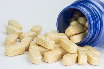 Fototapeta na wymiar Yellow tablets from a blue medicine jar.