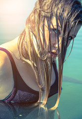 Junge Frau mit nassen Haaren steht im See und schaut den Betrachter an (Gegenlicht Flare)