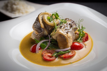 dorado with tomatoes on white plate