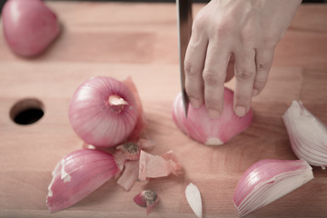 Obraz na płótnie Canvas red onions being cut on a wooden board by a knife