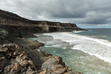 Fototapeta na wymiar Wave splashing over a rock on the beach of Puertito de los Molinos on Fuerteventura. Canary Island, Spain