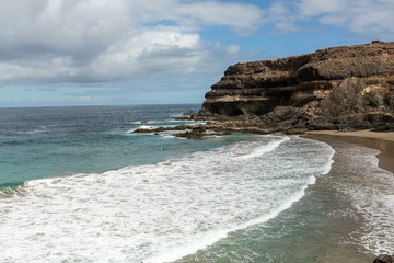 Wave splashing over a rock on the beach of Puertito de los Molinos on Fuerteventura. Canary Island, Spain