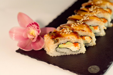 Eel sushi roll, decorated with sesame, on slate texture close up