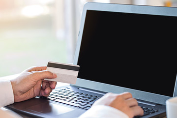 Business Man Payment Online by Credit Card and Laptop over blurred office on morning sun light,...
