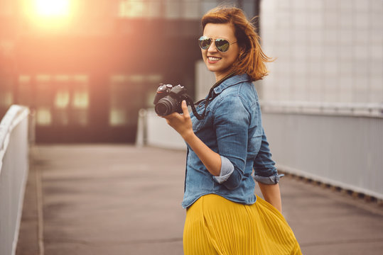Woman photographer walking in foreigh city with DSLR camera in hand