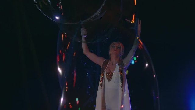 Woman is doing soap bubble show on the black background