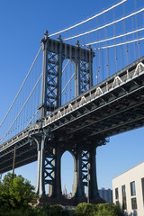 Close up of the Brooklyn tower of the Manhattan Bridge from the greenery in the park in DUMBO (Down Under the Manhattan Bridge Overpass) in New York City