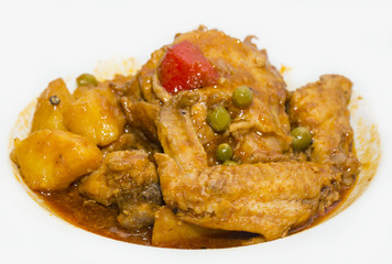 chicken curry with vegetables on a white plate in a restaurant