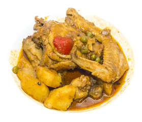 chicken curry with vegetables on a white plate in a restaurant