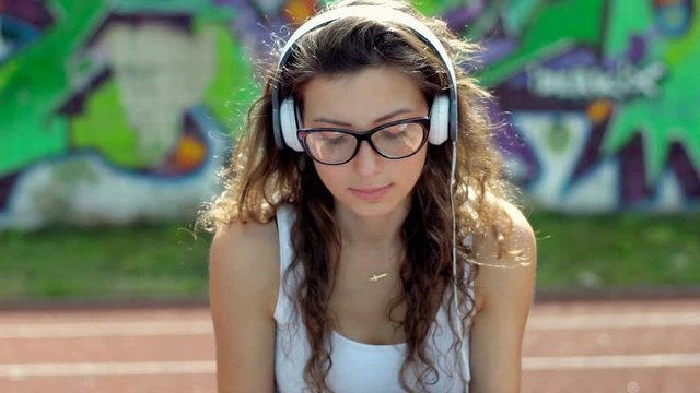 Thoughtful girl listening music on headphones and bouncing ball
