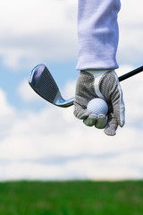 Hand with golf ball on the background of the sky