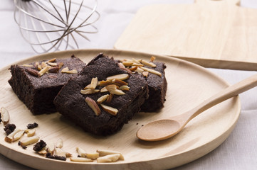 Three brownies in wood dish with spoon.