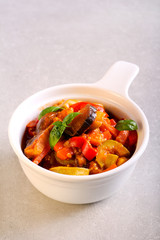 Vegetable stew in a bowl over grey background