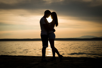 silhouette teenager lovers couple on sunset dusk sky background at the beach:black shadow hand...